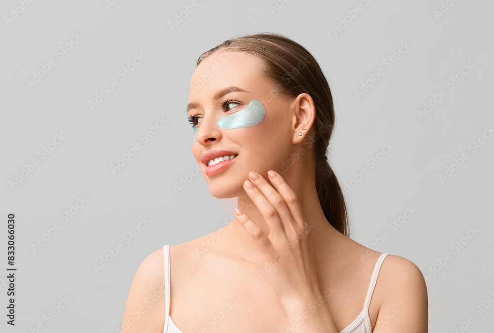 Beautiful young happy woman with healthy skin and under-eye patches on grey background Beautiful young happy woman with healthy skin and under-eye patches on grey background