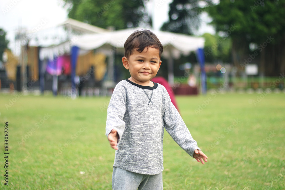 A handsome young boy, nicely dressed showing an expression of joy with hands up in the air looking excited and happy to be playing outdoors A handsome young boy, nicely dressed showing an expression of joy with hands up in the air looking excited and happy to be playing outdoors