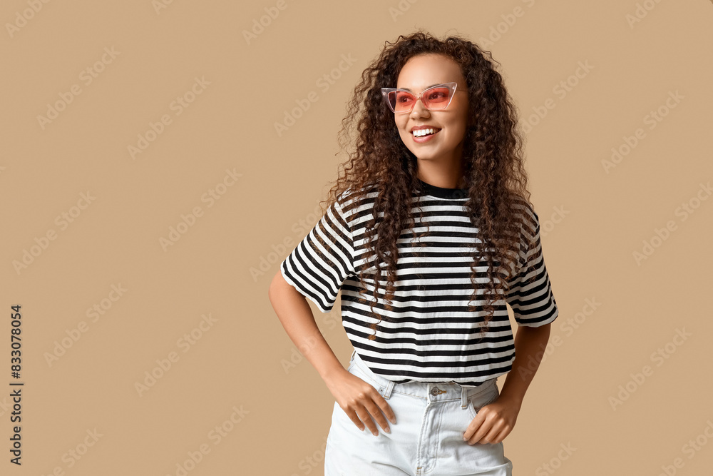 Happy young African-American woman in sunglasses on beige background Happy young African-American woman in sunglasses on beige background