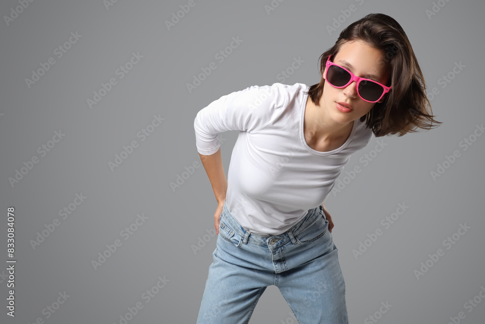 Beautiful young woman in stylish jeans on grey background Beautiful young woman in stylish jeans on grey background