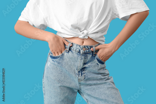 Beautiful young woman in stylish jeans on blue background, closeup © Pixel-Shot