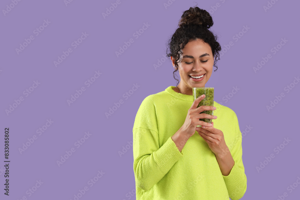 Beautiful young happy African-American woman with glass of tasty kiwi smoothie on purple background Beautiful young happy African-American woman with glass of tasty kiwi smoothie on purple background