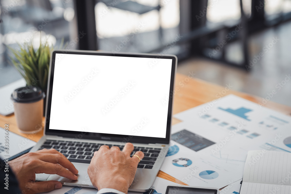 Person using a laptop with a blank screen at a desk with charts and graphs. Ideal for business, work, or technology concept stock photos. Person using a laptop with a blank screen at a desk with charts and graphs. Ideal for business, work, or technology concept stock photos.