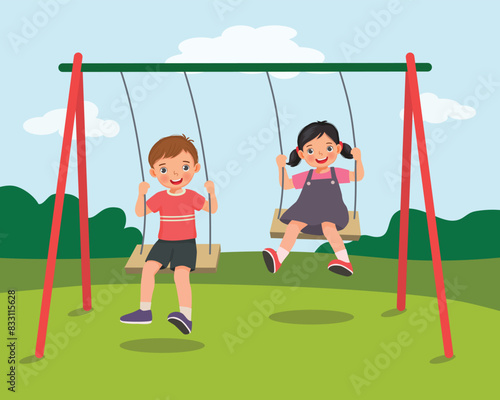 cute little kids boy and girl swinging and having fun on rope wooden swing in playground photo