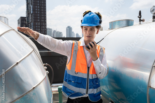 Portrait Asia male engineer in protective workwear is performing a conducts system check with use walkie talkie at rooftop building	