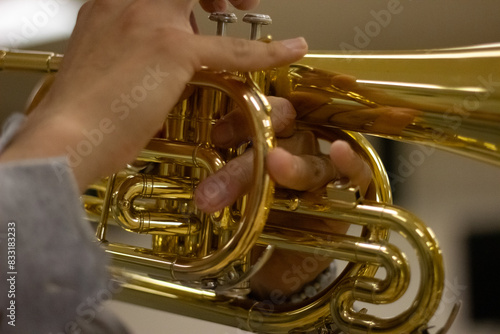 Close-up of hands playing a shiny brass mellophone. photo