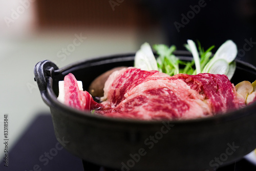 Traditional Japanese hot pot with tender premium Wagyu beef slices and fresh vegetables in a rustic cast iron pot closeup