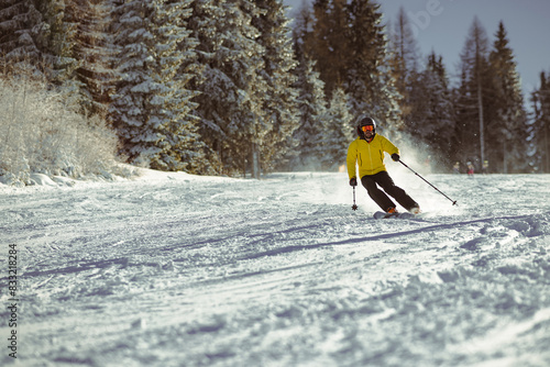 Obraz na płótnie Young person in fashionable clothes is skiing towards the camera on a ski slope on a sunny day. Carve or carving on ski piste, perfect weather, strong backlight. w salonie