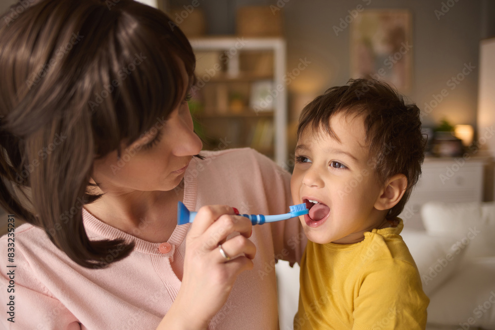 Mother teaching and helping her son brush his teeth at home Mother teaching and helping her son brush his teeth at home