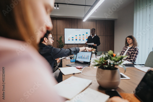A diverse group of young business professionals collaborate in a meeting room, analyzing financial data and planning future company investments.