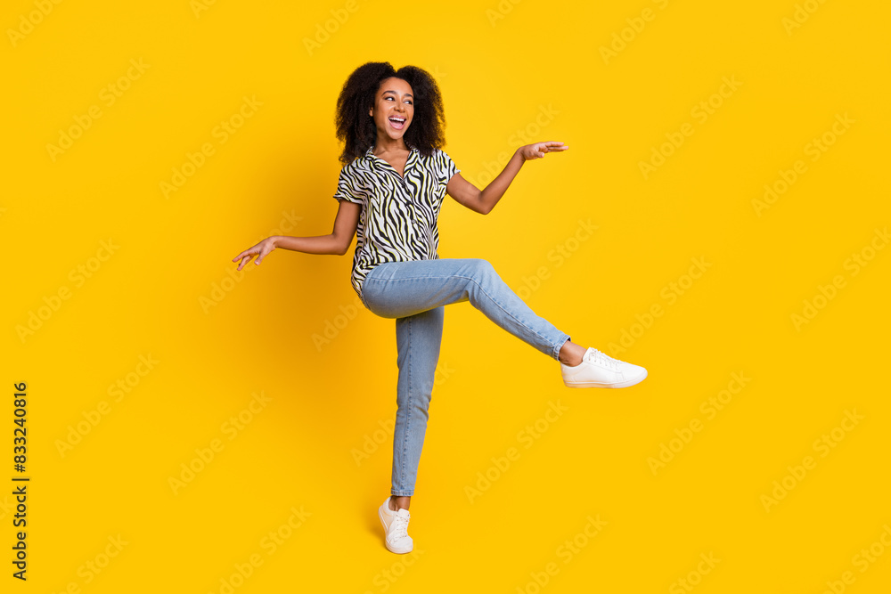 Photo of glamour young charming woman curly hair in zebra print shirt and jeans dancing boogie woogie isolated on yellow color background