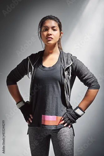 Obraz Portrait, woman and confidence for fitness and empowerment, serious and light on gray background. Workout, strong and exercise for athlete person, gloves and training in studio for personal trainer