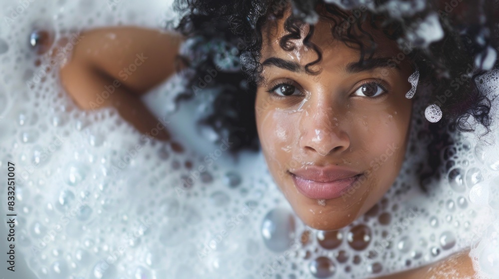 Fototapeta premium A woman with curly hair is in a bathtub with bubbles