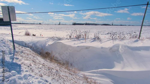 A rural farm field covered in a layer of snow and ice after a snowstorm, a strong chilly wind blows ice across the surface of the field, Canada photo