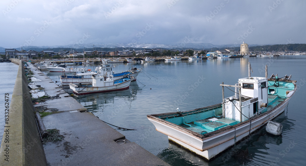 Fototapeta premium Japanese Suzu fishing port, harbor with moored fishing boats and village in background, Noto peninsula, Japan