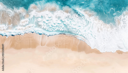 Aerial shot of tropical coastline with turquoise water, white foam waves, and yellow sand.