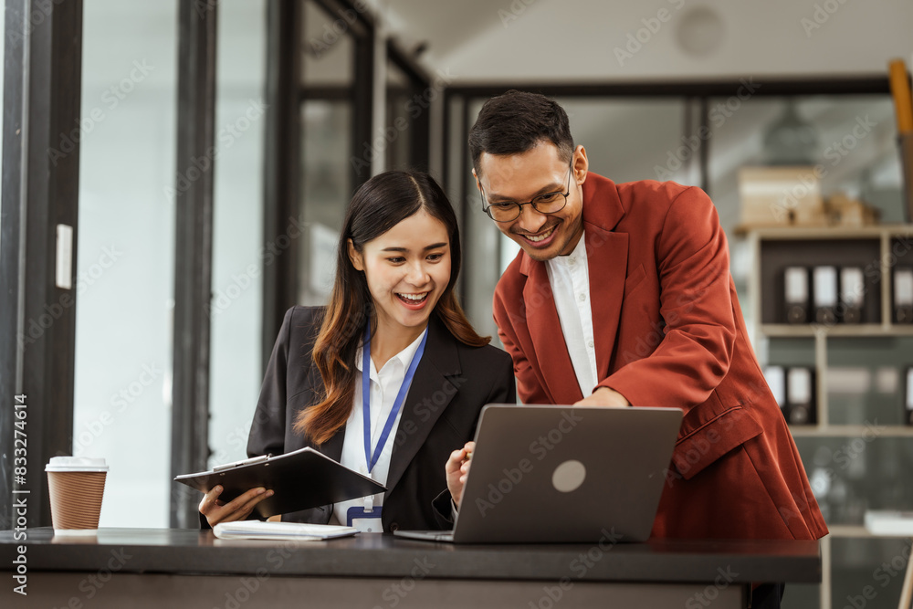 Middle-aged businessman and young Asian businesswoman diligently working at desks, managing tasks as recruitment, training, performance management, inclusive organizational culture. Middle-aged businessman and young Asian businesswoman diligently working at desks, managing tasks as recruitment, training, performance management, inclusive organizational culture.
