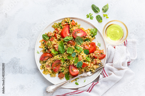 Tabbouleh o tabulè salad, Arab dish from the Middle East and Mediterranean, with parsley, bulgur, onions, mint and tomatoes, seasoned with lemon juice, olive oil,  white table photo