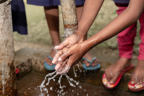 Children washing their hands at an outdoor water tap. Keep your hands clean. current affairs 2020. covid19 wash your hands campaign. © Anupam