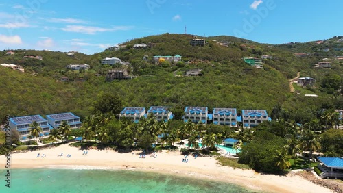 wide drone shot of hotels on secluded island showing beautiful beach on sunny day in st. thomas