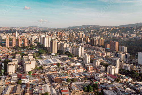 Aerial view of Caracas at sunset with the David Tower landmark skyscraper and slums visible. Drone shot of the venezuelan capital at sunset. Concept of development in a developing country