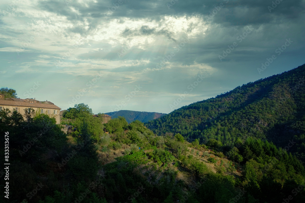 The mountainous area has lush vegetation, traditional buildings, and scenic skies brightened by the sun The mountainous area has lush vegetation, traditional buildings, and scenic skies brightened by the sun