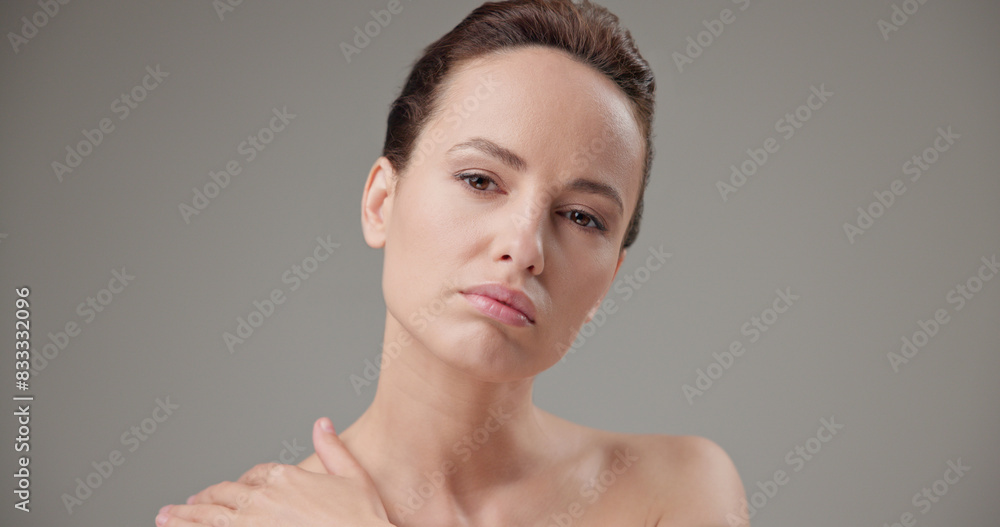 Beauty, health, cosmetics, anti-aging therapy and skin care concept - young beautiful brunette Caucasian woman touching face and looking at camera Beauty, health, cosmetics, anti-aging therapy and skin care concept - young beautiful brunette Caucasian woman touching face and looking at camera