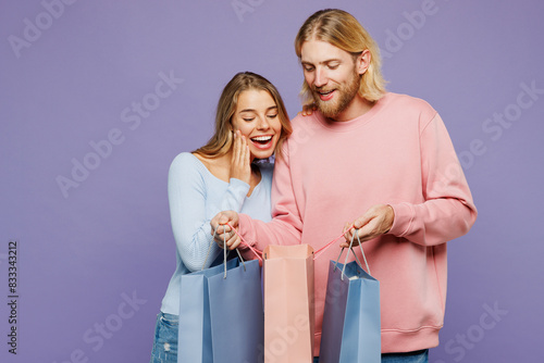 Wallpaper Mural Young surprised fun amazed couple two friends family man woman wearing pink blue casual clothes hold shopping paper package bags isolated on plain purple background. Black Friday sale buy day concept. Torontodigital.ca