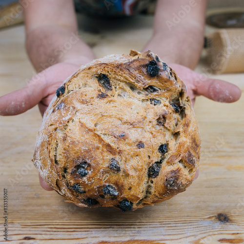 Artisan Fruit Bread Held in Hands Against Rustic Background