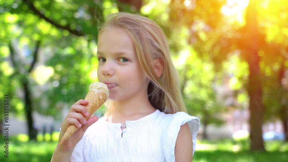 Cute little girl eating ice cream. Happy girl eating ice cream cone smiling while resting in park on summer day, child enjoying ice cream outdoor. Cute little girl eating ice cream. Happy girl eating ice cream cone smiling while resting in park on summer day, child enjoying ice cream outdoor.