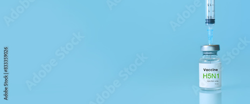 Vaccine vial of H5N1 in a bottle with a syringe on a blue background. Bird flu vaccine. The concept of medicine, healthcare and science. Copy space for text. Banner photo