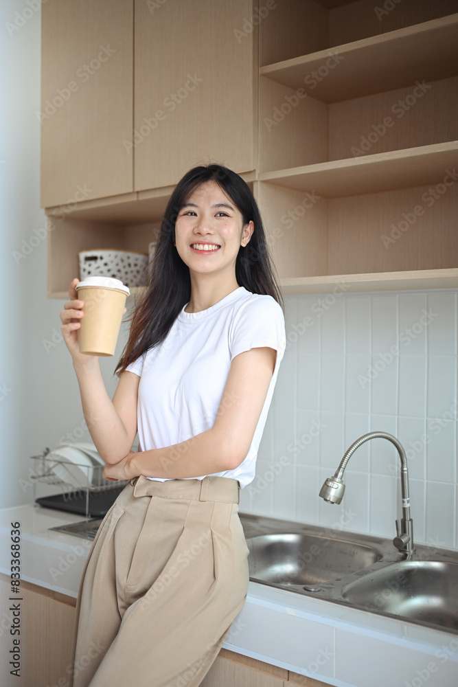 Charming young Asian woman enjoying fresh aromatic coffee standing in the kitchen Charming young Asian woman enjoying fresh aromatic coffee standing in the kitchen