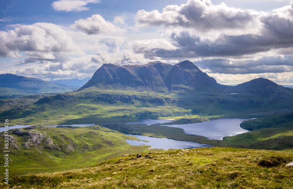 Views of the summits of Cul Mor and An Laogh with Loch an Doire Dhuibh below from the summit of Stac Pollaidh in the Scottish Highlands on a sunny summers day with dramatic clouds in the UK