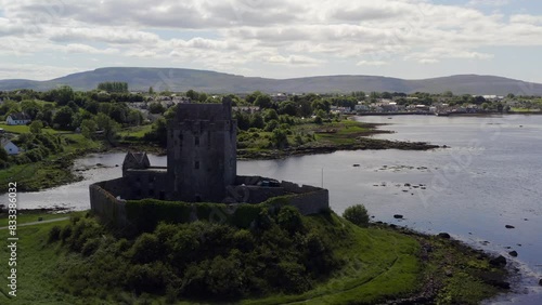 Calm orbiting shot of Dunguaire Castle. Kinvara in the background. Sunny day photo