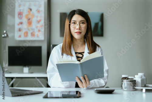 Successful female doctor sitting at a desk, looking at the camera.