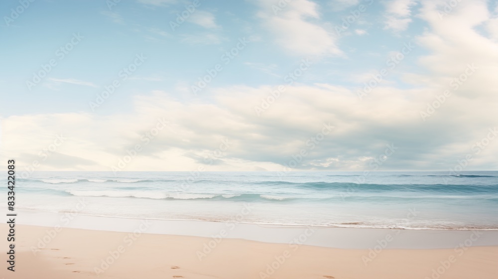 A serene beach scene with gentle waves, a blue sky filled with clouds, and footprints in the sand.