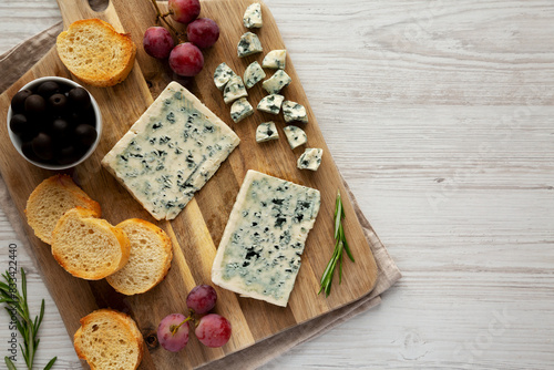 Organic Blue Cheese with Grapes and Olives on a Wooden Board, top view. Copy space.