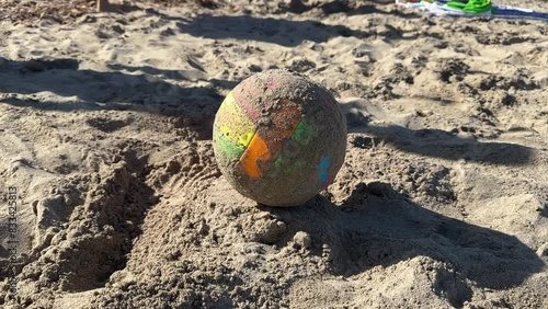 Right-handed person with his bare foot hits a beach soccer ball in the sand. Conceotp of vacation, fun, summer, sport and hitting.