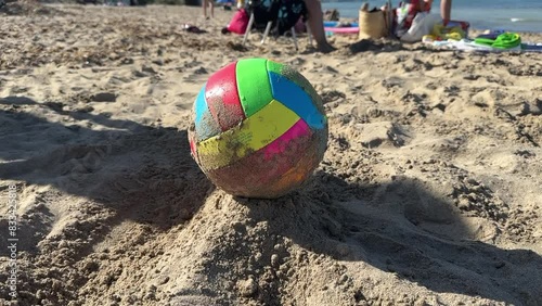 Right-handed person with his bare foot hits a beach soccer ball in the sand. Conceotp of vacation, fun, summer, sport and hitting.