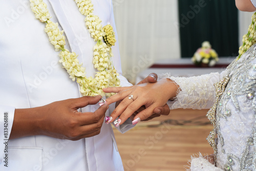 The bride, wedding ring, and groom hold hands. Showing the warmth of their relationship, love and respect for each other.