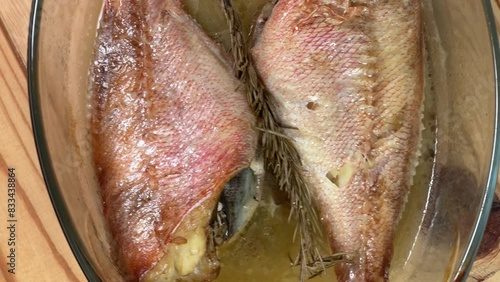 Baked redfishes in old glass baking dish on rustic table photo