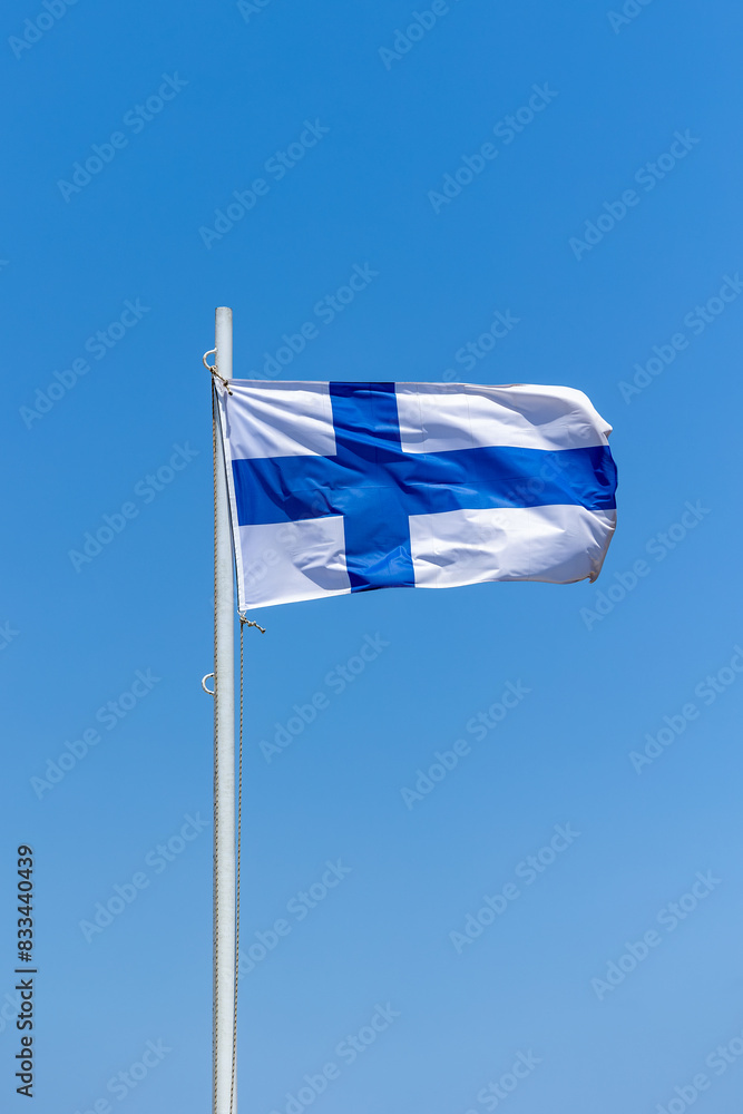 Fototapeta premium Finland flag attached to pole waving in the wind cloudless blue sky background