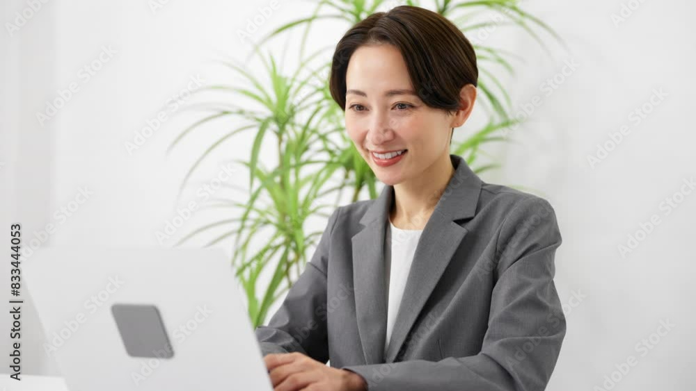 ビジネススーツを着てラップトップを操作している若い女性　ビジネスイメージ