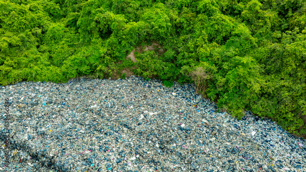 Obraz premium Aerial view, piles of garbage, plastic bottles and trash, and forests. Concept of waste disposal and separation to preserve the environment and save the planet.