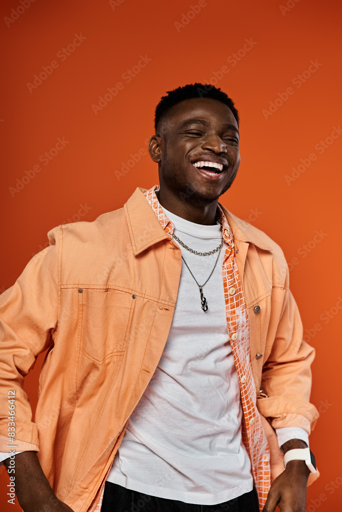 Handsome man in orange jacket smiling against orange backdrop. Handsome man in orange jacket smiling against orange backdrop.