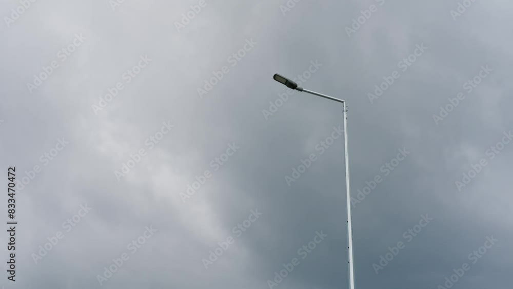 Single street lamp standing against a backdrop of cloudy and overcast sky. Minimalistic and lonely scene. Single street lamp standing against a backdrop of cloudy and overcast sky. Minimalistic and lonely scene.