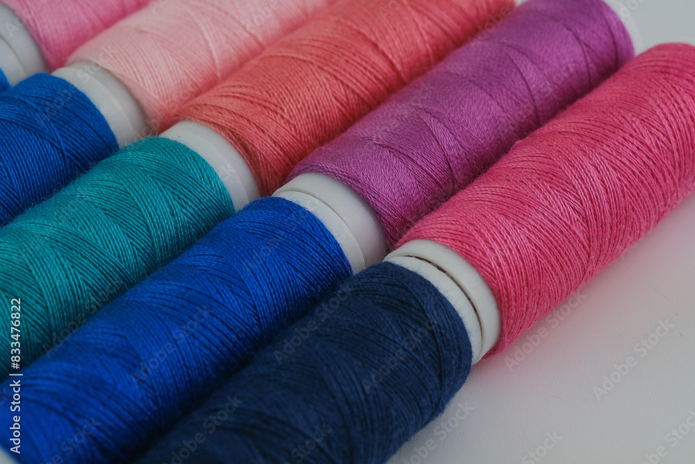 Numerous spools of thread neatly arranged in a row next to each other Numerous spools of thread neatly arranged in a row next to each other
