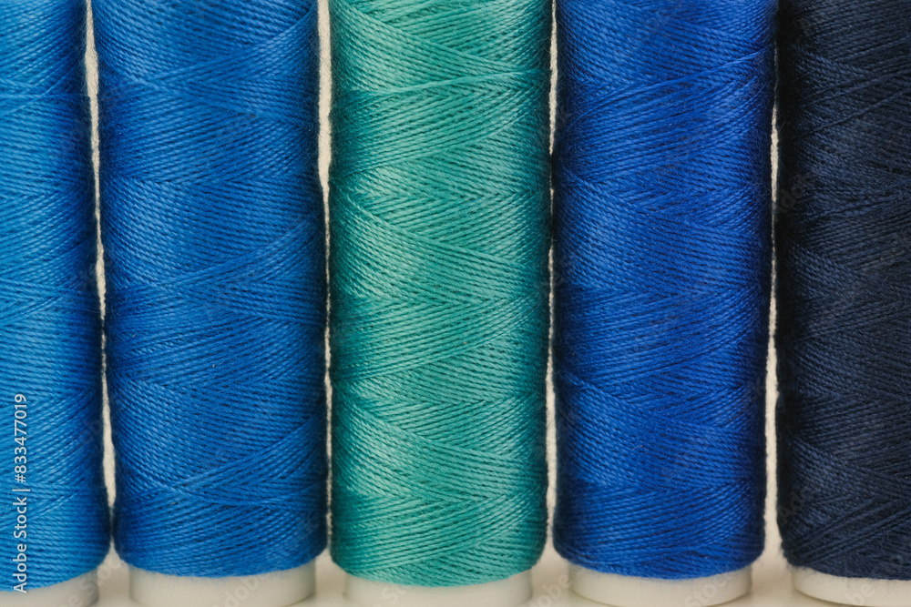 Several spools of thread lined up next to each other on a surface Several spools of thread lined up next to each other on a surface