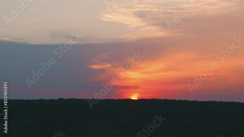 The horizon glows with beautiful hues of orange and pink during a stunning sunset over the hilly landscape photo