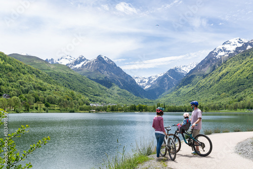 Family spending a nice spring day with their bikes around a beautiful lake surrounded by mountains in Louron Valley, french pyrenees.